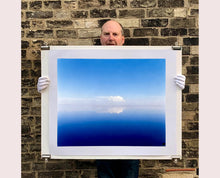 Load image into Gallery viewer, 'View from Bombay Beach' looks over Salton Sea in California. Cooling shades of blue, reflection and symmetry are key to this serene waterscape. The suspended cloud which looks surreal creates a feeling of weightlessness. 