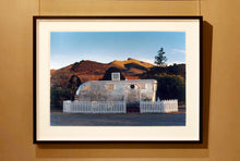 Load image into Gallery viewer, This artwork brings about a romantic dream of living in an RV. Captured in the morning sun at the start of a beautiful Arizona day, this RV is surrounded by both a white picket fence and a beautiful landscape, with the sun tickling the hilltops. Photographed as part of Richard Heeps' 'Dream in Colour' series.