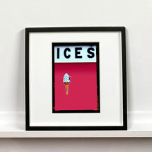 Load image into Gallery viewer, Black framed photograph by Richard Heeps.  At the top black letters spell out ICES and below is depicted a 99 icecream cone sitting left of centre against a raspberry coloured background.  