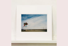 Load image into Gallery viewer, Part of the 'Dream in Colour' series, 'Roy's - Route 66' is one of Richard Heeps' classic American sign artworks featuring the road sign for Roy's Motel, which demonstrates historic Mid-Century Modern Googie architecture. This photograph was capture on the National Trails Highway of U.S. Route 66, in the Mojave Desert town of Amboy in San Bernardino County, California.