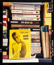 Load image into Gallery viewer, ‘Scientific Sexology’ sits amongst a stack of books, captured in Milan, Italy. 
