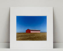 Load image into Gallery viewer, 'Stars &amp; Stripes Barn' shows a depiction of the American flag painted on this isolated building in Oakhurst, California. It sits on the horizon against a vast bright blue sky. This artwork is part of Richard Heeps' 'Dream in Colour' series.