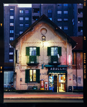 Load image into Gallery viewer, The traditional Italian Tobacconist shop, here in a Swiss Cottage style building set against a vast urban apartment block. 