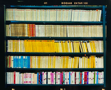 Load image into Gallery viewer, As part of Richard Heeps' series, A Short History of Milan, The Last Kiss features a series of yellow, blue and pink Italian books.