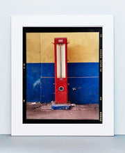 Load image into Gallery viewer, A red retro tyre pump against a yellow and blue painted wall, in the Porta Genova area of Milan. 