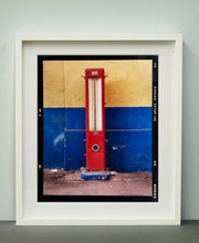 Load image into Gallery viewer, A red retro tyre pump against a yellow and blue painted wall, in the Porta Genova area of Milan. 
