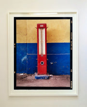 Load image into Gallery viewer, A red retro tyre pump against a yellow and blue painted wall, in the Porta Genova area of Milan. 