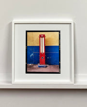 Load image into Gallery viewer, A red retro tyre pump against a yellow and blue painted wall, in the Porta Genova area of Milan. 