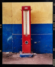 Load image into Gallery viewer, A red retro tyre pump against a yellow and blue painted wall, in the Porta Genova area of Milan. 