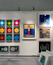Load image into Gallery viewer, A red retro tyre pump against a yellow and blue painted wall, in the Porta Genova area of Milan. 