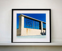 Load image into Gallery viewer, 'Window of the World, Zzyzx Resort Pool', photographed in Soda Dry Lake, California shows window pains and a distressed wall, against a bright blue background of sky. This artwork is part of Richard's 'Dream in Colour' series. 