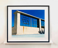 Load image into Gallery viewer, 'Window of the World, Zzyzx Resort Pool', photographed in Soda Dry Lake, California shows window pains and a distressed wall, against a bright blue background of sky. This artwork is part of Richard's 'Dream in Colour' series. 