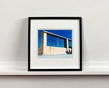 Load image into Gallery viewer, 'Window of the World, Zzyzx Resort Pool', photographed in Soda Dry Lake, California shows window pains and a distressed wall, against a bright blue background of sky. This artwork is part of Richard's 'Dream in Colour' series. 