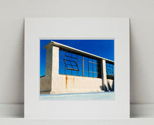 Load image into Gallery viewer, 'Window of the World, Zzyzx Resort Pool', photographed in Soda Dry Lake, California shows window pains and a distressed wall, against a bright blue background of sky. This artwork is part of Richard's 'Dream in Colour' series. 