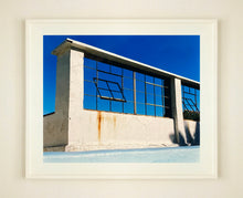 Load image into Gallery viewer, 'Window of the World, Zzyzx Resort Pool', photographed in Soda Dry Lake, California shows window pains and a distressed wall, against a bright blue background of sky. This artwork is part of Richard's 'Dream in Colour' series. 