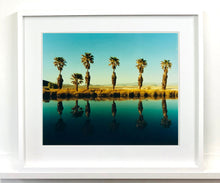 Load image into Gallery viewer, Plam trees stand tall against ombre skies in shades of blue and green in 'Zzyzx Resort Pool II', taken in Soda Dry Lake, California. This artwork was taken on a road trip from LA to Las Vegas. This photograph was taken on negative in 2002 but only executed in Richard's darkroom for the first time in 2017.