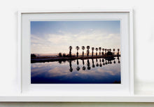 Load image into Gallery viewer, Zzyzx Resort Pool, part of Richard Heeps 'Dream in Colour' Series, he was set a challenge to find something interesting on the road from LA to Las Vegas. In the heart of the Mojave Desert, Richard found the former spa Zzyzx, an oasis. This dreamy artwork keeps the perfect summery palm print vibe all year round.